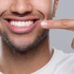 A man pointing to his smile showing healthy teeth from periodontal dentistry