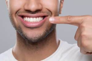 A man pointing to his smile showing healthy teeth from periodontal dentistry